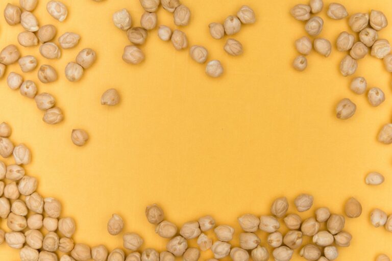 A close-up of chickpeas scattered on a vibrant yellow background, showcasing healthy legumes.