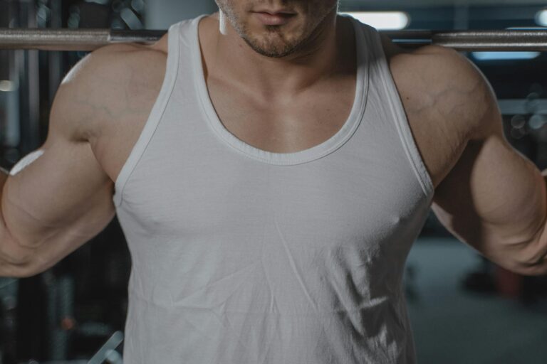 Close-up of a muscular man lifting weights in a gym, emphasizing strength and dedication.
