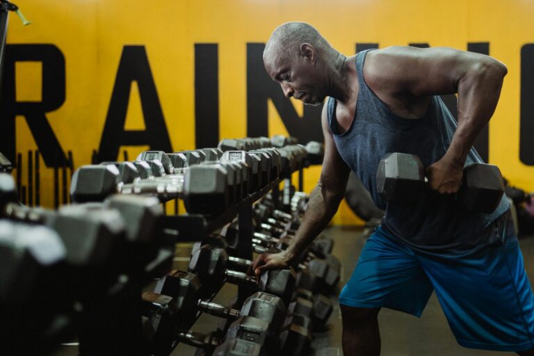 An athletic man lifting dumbbells in the gym, focusing on strength and fitness training.
