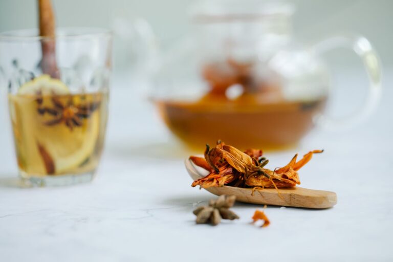 A beautifully composed image of herbal tea with star anise and dried flowers on a wooden spoon.