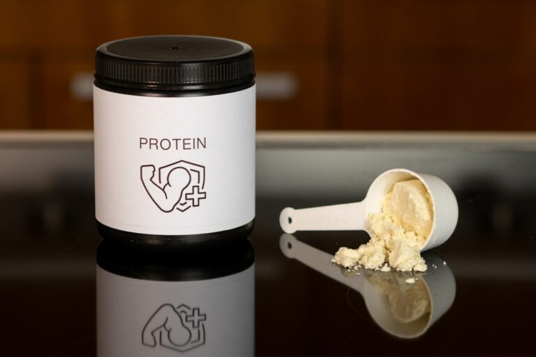 Um Recipiente De Proteina Em Po Ao Lado De Uma Colher 4CzpHxVzTFA