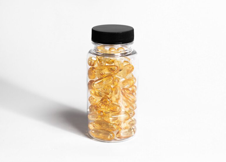 Close-up of a transparent bottle filled with yellow softgel capsules in a minimalist style.