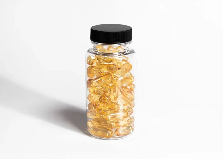 Close-up of a transparent bottle filled with yellow softgel capsules in a minimalist style.